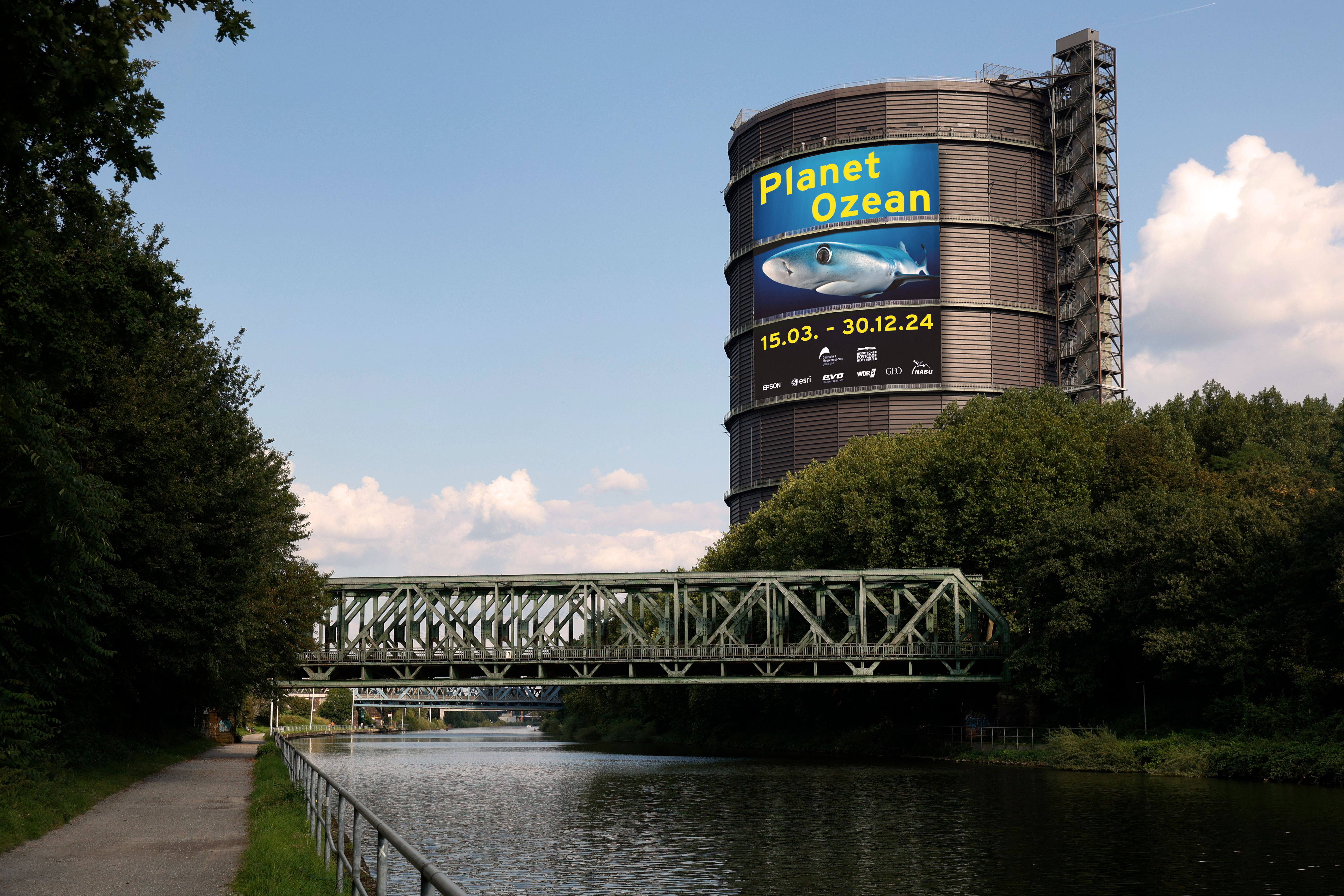 A large poster on the Rhine-Herne Canal indicates the Planet Ocean exhibition in the Gasometer