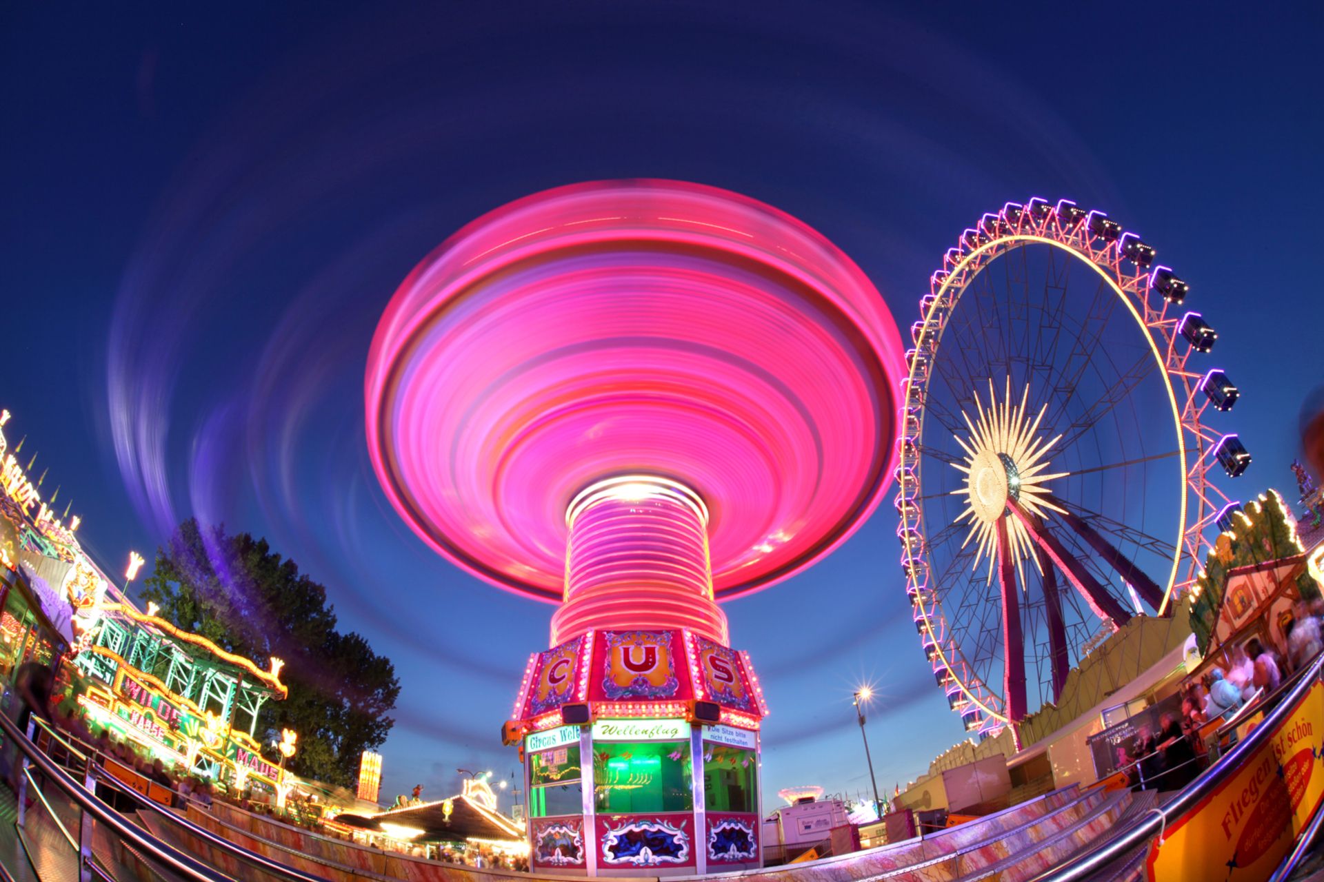 The chain carousel at the Cranger Kirmes lights up in bright colors in the dark as it makes its rounds