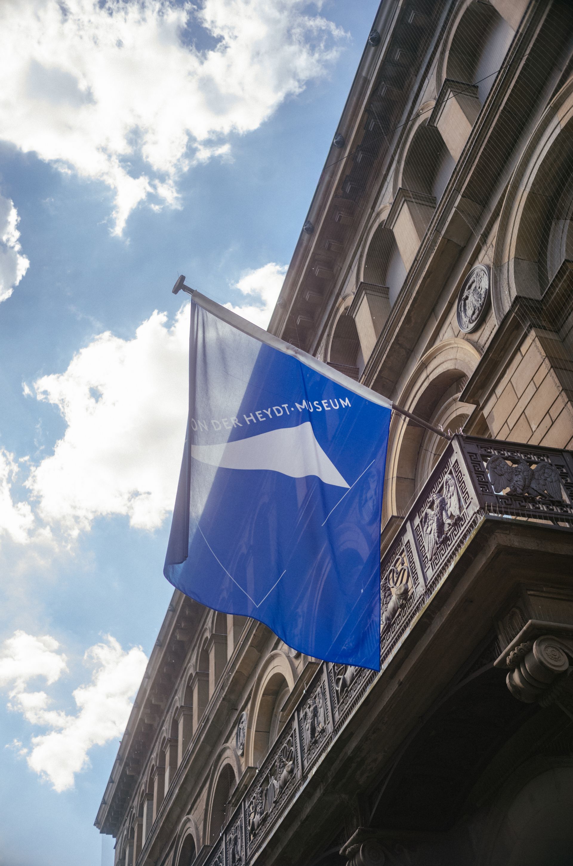 Die blau-weiße Flagge des Von der Heydt-Museums hängt vorm Eingang in der Wuppertaler Fußgängerzone