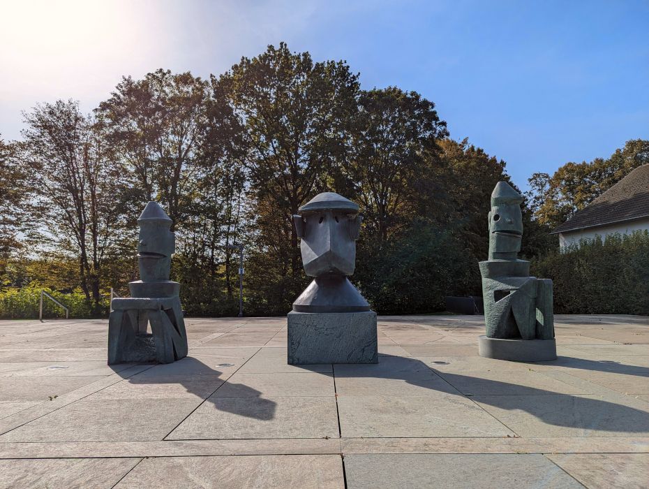 The three-part bronze sculpture Lehrerkollegium einer Schule für Totschläger by Max Ernst stands in front of the museum entrance